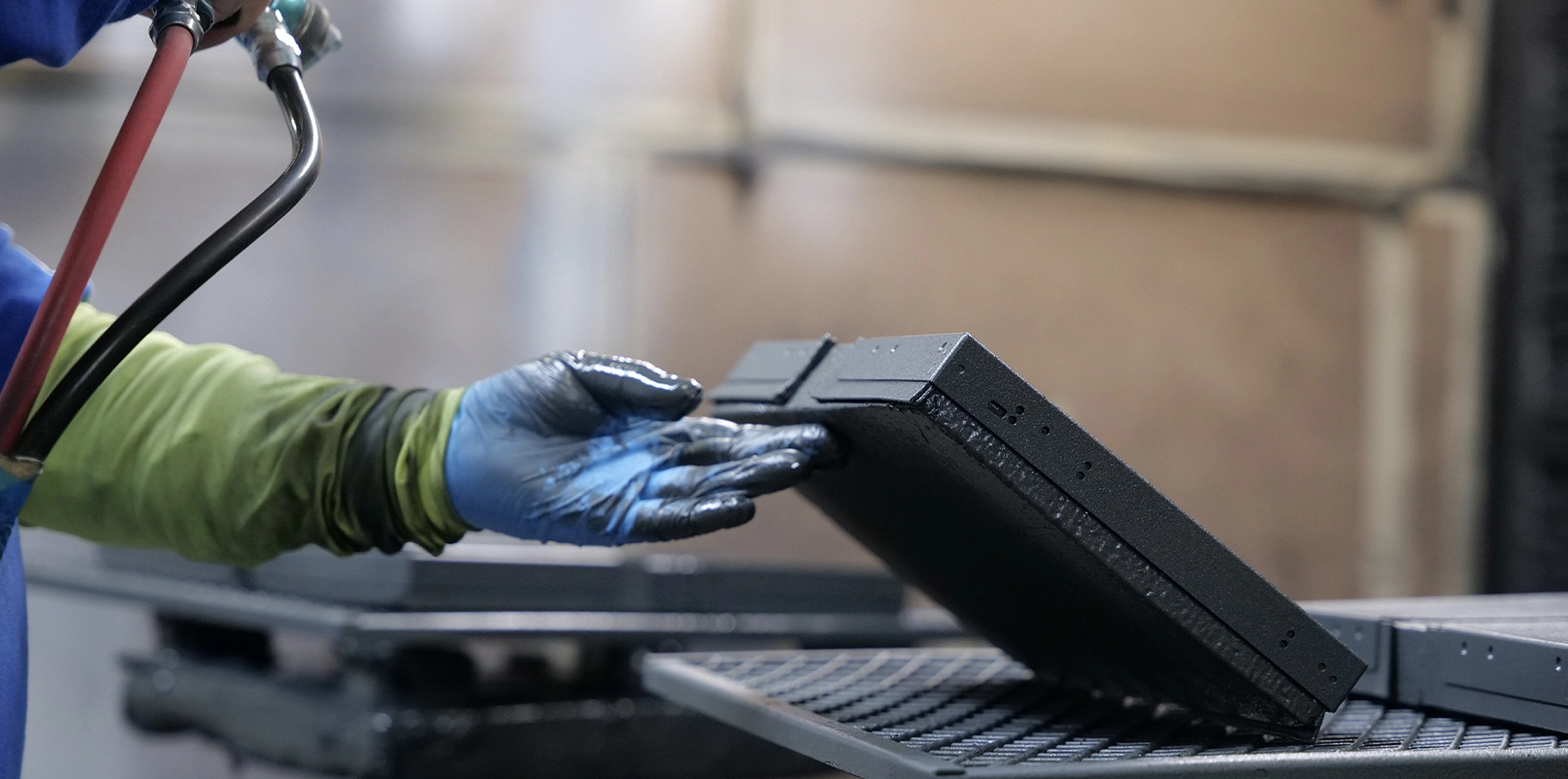 Pinnacle Finishing Team member powder coating a metal part before it finalizes production