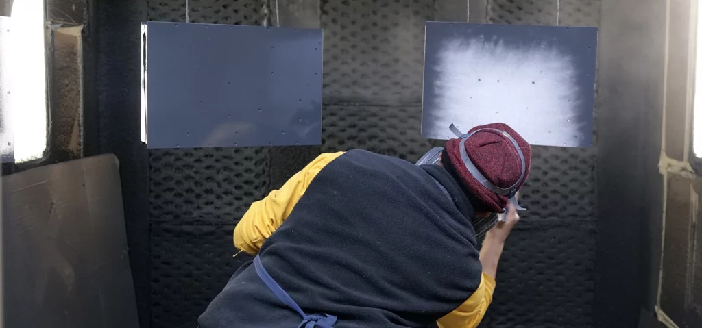 Finisher using powder coating techniques on a metal part in the final stages of the part production